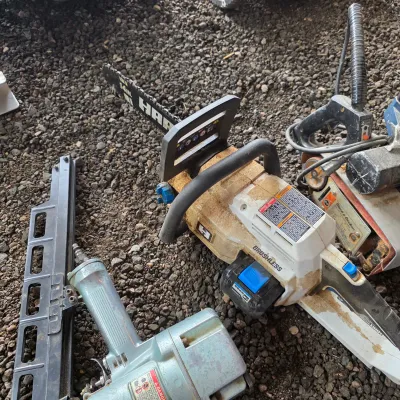 Sale Photo Thumbnail #46: Hart 14-inch brushless battery-powered chainsaw, shown alongside a pneumatic framing nailer and a vintage Black & Decker belt sander.