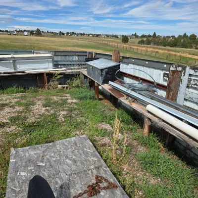 Sale Photo Thumbnail #83: Assorted outdoor building materials, metal pipes, and a vintage metal storage chest arranged on wooden benches in a rural yard.