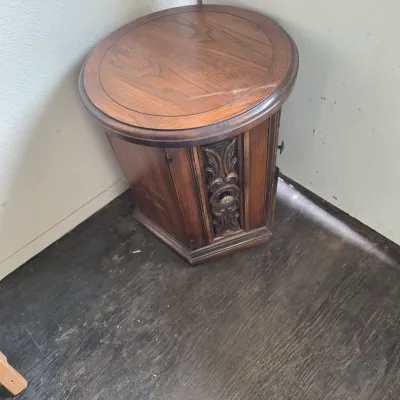Sale Photo Thumbnail #15: Vintage hexagonal oak commode end table featuring a round top, carved decorative front panel, and integrated storage cabinet.