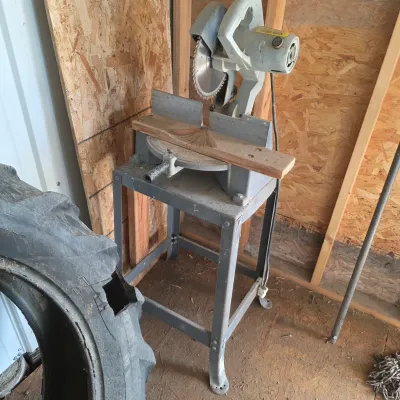 Sale Photo Thumbnail #86: Vintage power miter saw mounted on a grey metal utility stand, showing signs of use and wear.