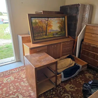 Sale Photo Thumbnail #3: Assorted vintage bedroom furniture, including oak-veneer dressers, a nightstand frame, mattresses, and a large framed autumn landscape oil painting.