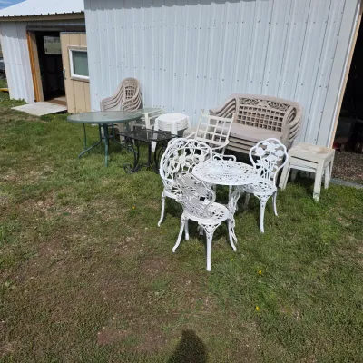 Sale Photo Thumbnail #89: Assorted outdoor furniture including a white cast aluminum bistro set, a glass-top patio table, and various plastic lawn chairs and benches.