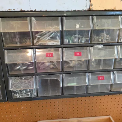 Sale Photo Thumbnail #66: Vintage metal multi-drawer organizer cabinet with clear plastic tilt-out bins, containing various screws, brackets, and hardware.