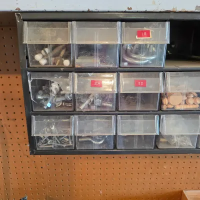 Sale Photo Thumbnail #65: Vintage metal multi-drawer organizer filled with various hardware, including screws, bolts, hooks, and wooden plugs.