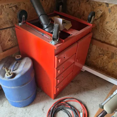 Sale Photo Thumbnail #92: Red metal rolling tool cabinet with drawers and a side cabinet, shown upside down with casters attached, alongside a blue plastic drum and extension cords.