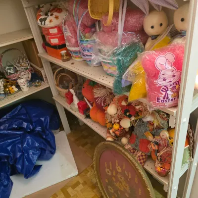 Sale Photo Thumbnail #19: Assorted holiday decorations on metal shelving, featuring Easter baskets, plush bunnies, colorful Easter grass, and autumn-themed scarecrow dolls.