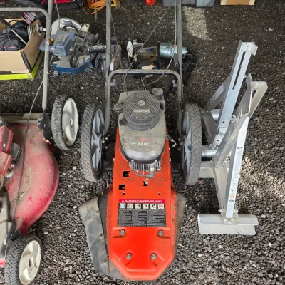 Sale Photo Thumbnail #51: Ariens 6.0 HP walk-behind string trimmer alongside a red lawn mower and an aluminum ladder jack.