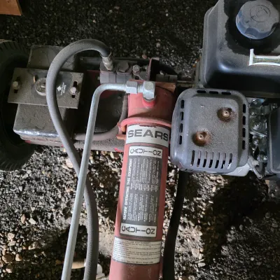 Sale Photo Thumbnail #34: Vintage Sears hydraulic log splitter showing the engine, hydraulic cylinder, and safety warning labels.