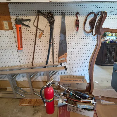 Sale Photo Thumbnail #62: Assorted workshop tools and garage items, including a hand saw, bow saw, caulking gun, aluminum extension ladder, and a red fire extinguisher.