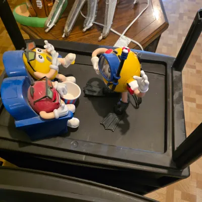 Sale Photo Thumbnail #22: Vintage M&M's character collectibles, including a 3D movie theater candy dispenser and a scuba diver figure.