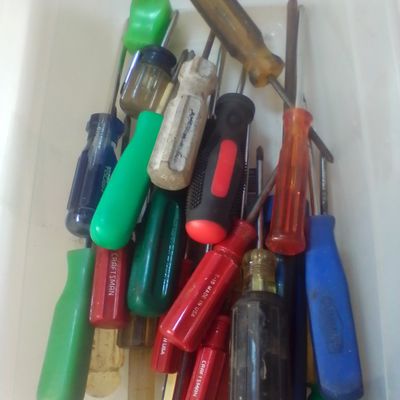 An Assortment of Craftsman and Mixed Brand Screwdrivers in a Clear Plastic Bin