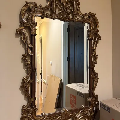 Ornate Rococo-style wall mirror with a carved gilded frame and intricate crest detail.