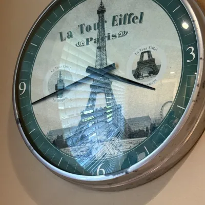 Round wall clock with a metal frame, featuring a vintage Paris and Eiffel Tower themed dial.
