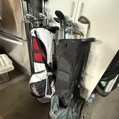 Two modern stand golf bags containing assorted drivers, irons, and putters.
