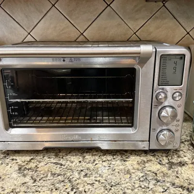Breville Smart Oven stainless steel countertop toaster oven featuring an LCD screen, multiple cooking functions, and rotary control dials.