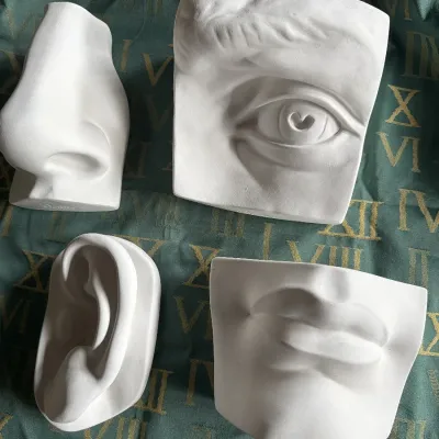 Set of four classical plaster artist study casts depicting facial features, including an eye, nose, ear, and lips.