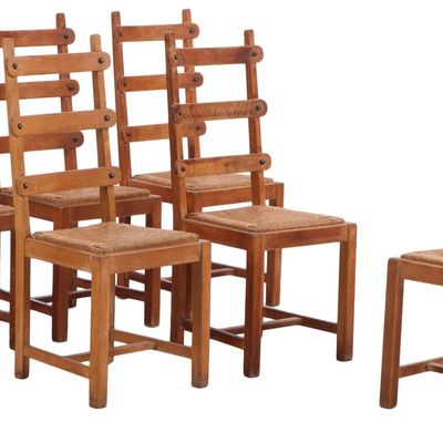ONE OF TWO SETS OF OAK BRUTALIST STYLE RUSH SEAT DINING CHAIRS HAVING METAL TACK DECORATION C 1950.