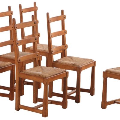 ONE OF TWO SETS OF OAK BRUTALIST STYLE RUSH SEAT DINING CHAIRS HAVING METAL TACK DECORATION C 1950.