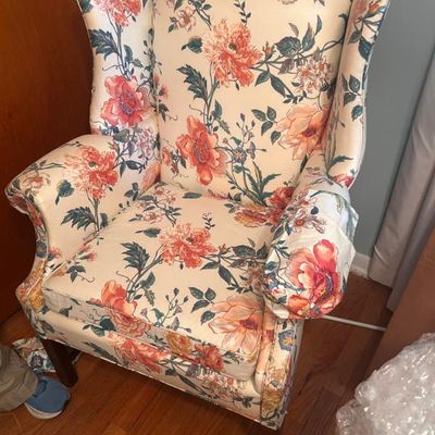 Sale Photo Thumbnail #84: Traditional wingback armchair featuring a vibrant floral pattern in shades of orange, pink, and green on a cream background.