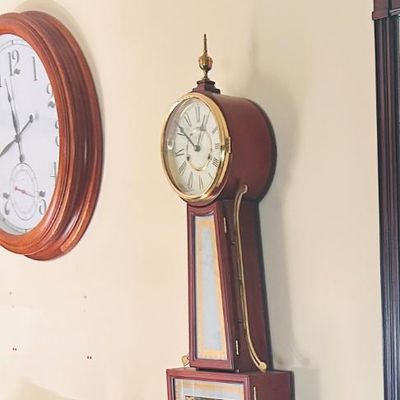 Sale Photo Thumbnail #60: Vintage mahogany banjo wall clock featuring a brass finial, side brackets, and decorative glass panels.
