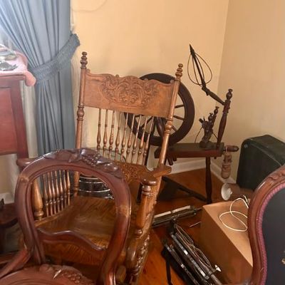 Sale Photo Thumbnail #51: Antique wooden rocking chair with carved detailing and spindle back, shown alongside a vintage wooden spinning wheel.