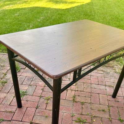 Sale Photo Thumbnail #90: Rectangular dining table featuring a wood-look laminate top and a black metal frame with decorative scrollwork.