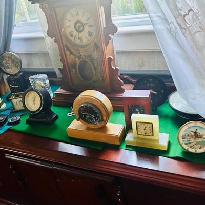Sale Photo Thumbnail #34: Collection of vintage clocks, featuring an antique wooden pendulum mantel clock alongside various mid-century and retro tabletop alarm clocks.