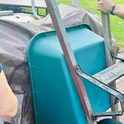 Sale Photo Thumbnail #26: True Temper wheelbarrow featuring a green plastic tub, wooden handles, and a single front tire.