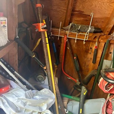 Sale Photo Thumbnail #96: Assorted hand tools and garden equipment, including a pipe clamp, bow saw, hammer, and various long-handled tools.