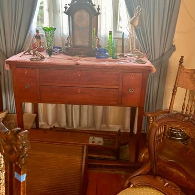 Sale Photo Thumbnail #18: Antique wooden sideboard with drawers, displaying a vintage mantle clock, glassware, and decorative items.