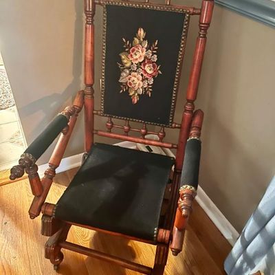 Sale Photo Thumbnail #46: Antique Eastlake-style platform rocking chair featuring a turned wood frame, black upholstered seat and armrests, and a needlepoint floral back panel.