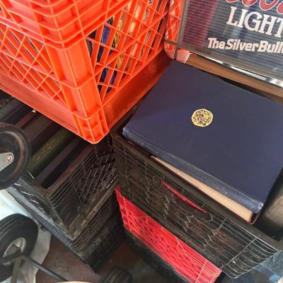 Sale Photo Thumbnail #101: Assorted vintage binders and books stored in plastic milk crates, alongside a Coors Light sign.
