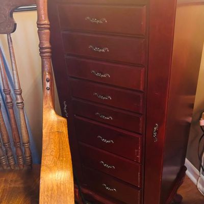 Sale Photo Thumbnail #49: Traditional cherry-finished standing jewelry armoire featuring eight drawers with ornate metal pulls and side cabinet doors.