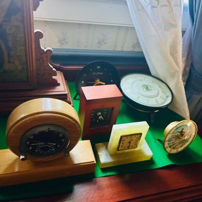 Sale Photo Thumbnail #121: Collection of vintage and modern table clocks, featuring various wooden, stone, and metal designs.