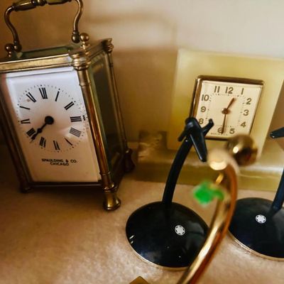 Sale Photo Thumbnail #86: Vintage Spaulding & Co. brass carriage clock alongside a square onyx desk clock and two Montblanc pen stands.