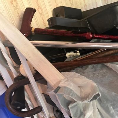 Sale Photo Thumbnail #91: Assorted walking canes, including a metallic red T-handle cane, a classic wooden curved-handle cane, and a silver metal cane.