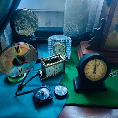 Sale Photo Thumbnail #32: Collection of vintage and novelty clocks, including a CD-faced clock, a small brass carriage clock, a crystal-encased desk clock, and various gauge-style timepieces.