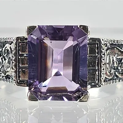 Vintage sterling silver ring featuring an emerald-cut purple amethyst gemstone set in an ornate, filigree-style band.