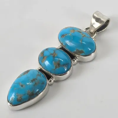 Southwestern-style sterling silver pendant featuring three graduated, bezel-set turquoise cabochons with natural matrix.