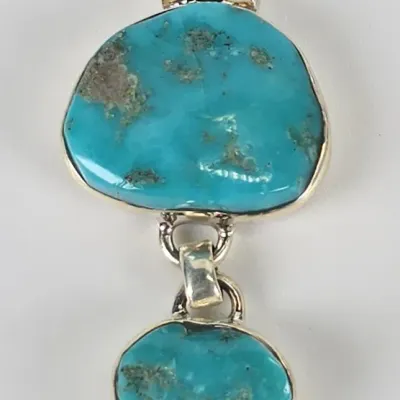 Two-tier sterling silver pendant featuring natural turquoise stones with visible matrix, in a Southwestern style.