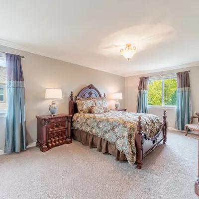Traditional cherry wood bedroom suite including a queen-size bed with an ornate carved headboard, matching three-drawer nightstands, and...