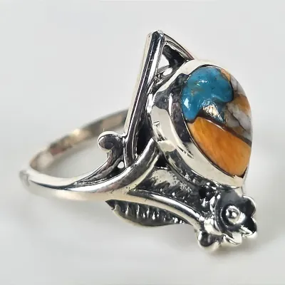 Sterling silver ring featuring a multi-stone inlay of turquoise and spiny oyster shell, accented with a floral and leaf motif.