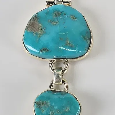 Two-tier sterling silver and turquoise pendant featuring natural turquoise stones with matrix inclusions, connected by a silver link.