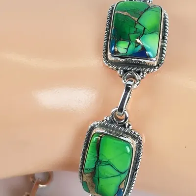 Sterling silver link bracelet featuring rectangular green turquoise stones with copper matrix in rope-textured bezel settings.