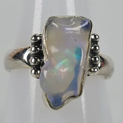 Sterling silver ring featuring a freeform raw opal stone with iridescent blue and green play-of-color, flanked by beaded silver accents.