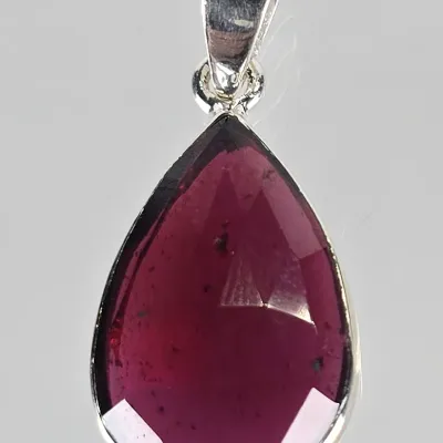 Teardrop-shaped faceted garnet pendant set in a sterling silver bezel with a polished bail.