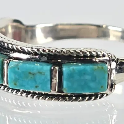 Sterling silver ring featuring rectangular turquoise inlay stones bordered by a twisted rope design, in Southwestern style.