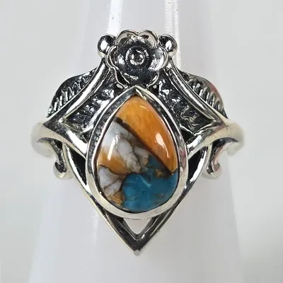 Sterling silver ring featuring a teardrop-shaped spiny oyster turquoise cabochon, accented by an ornate floral and leaf design.
