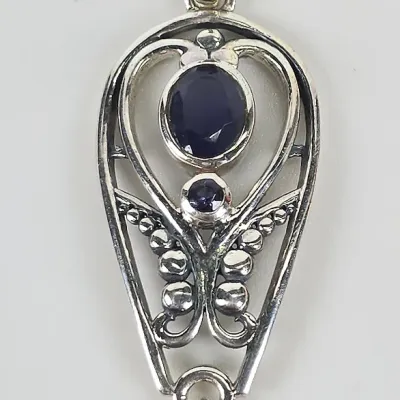 Sterling silver pendant featuring three dark blue, bezel-set gemstones in an openwork design with beaded accents and a teardrop dangle.