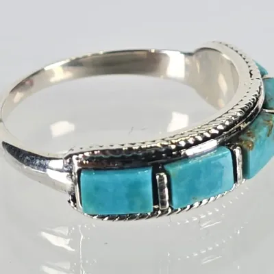 Sterling silver ring featuring a row of rectangular turquoise inlay stones bordered by a twisted rope detail.